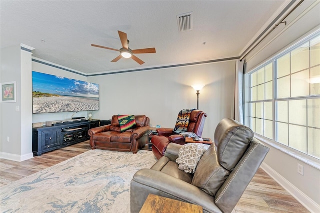 living room with ornamental molding, light hardwood / wood-style floors, a textured ceiling, and ceiling fan