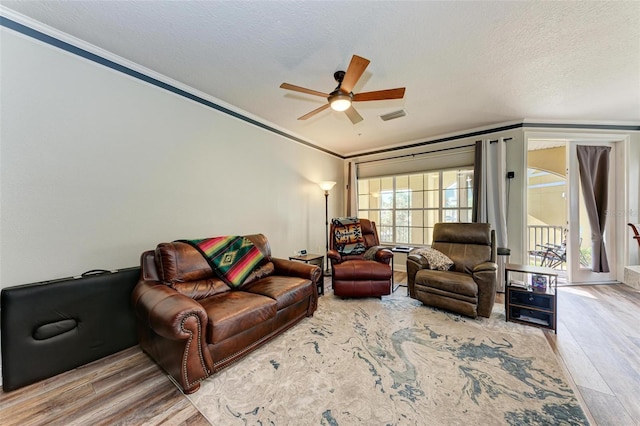 living room with a textured ceiling, wood-type flooring, ceiling fan, and crown molding