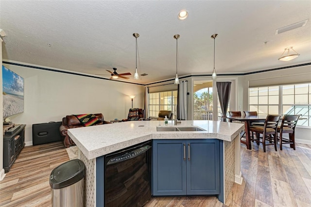 kitchen featuring a kitchen island with sink, dishwasher, blue cabinets, ceiling fan, and light hardwood / wood-style flooring