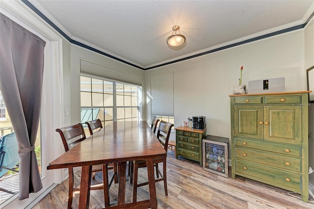 dining area with light wood-type flooring, a textured ceiling, and ornamental molding