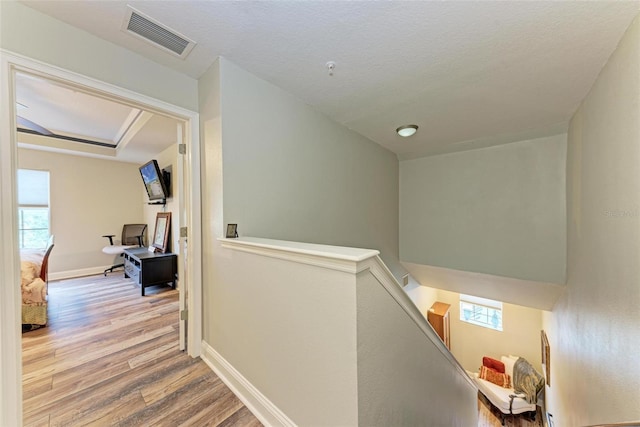 hall with a textured ceiling and light hardwood / wood-style floors