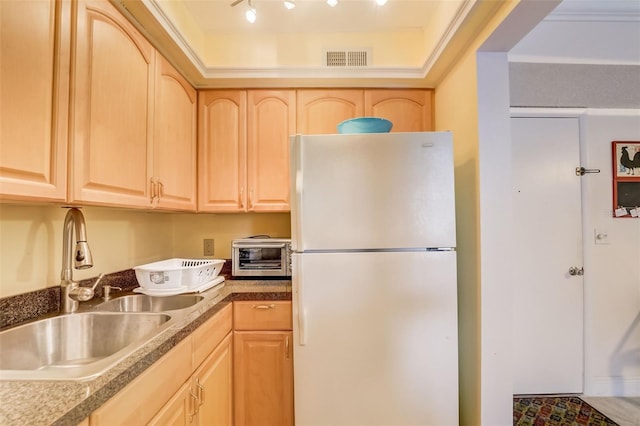 kitchen featuring light brown cabinets, white refrigerator, and sink