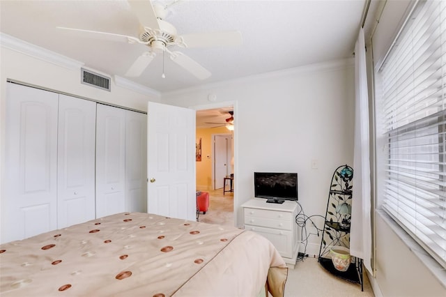 carpeted bedroom featuring ceiling fan, crown molding, and a closet