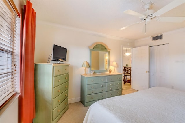 bedroom featuring ceiling fan, a closet, light colored carpet, and ornamental molding