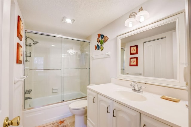 full bathroom with combined bath / shower with glass door, tile patterned floors, a textured ceiling, toilet, and vanity