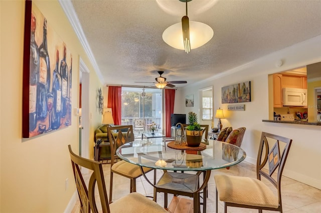 dining space with ceiling fan, ornamental molding, and a textured ceiling