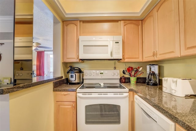 kitchen featuring dark stone countertops, light brown cabinets, and white appliances