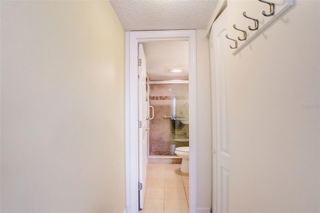 hall with light tile patterned floors and a textured ceiling