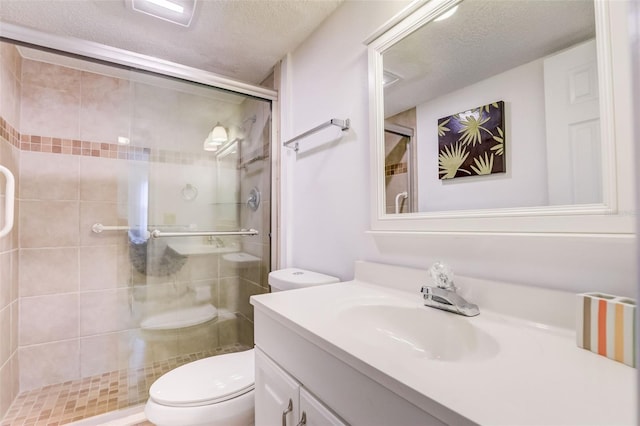 bathroom with vanity, toilet, a shower with door, and a textured ceiling