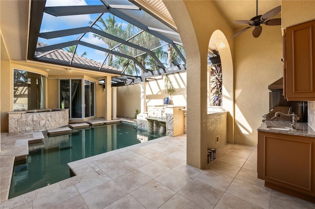 view of pool featuring ceiling fan, exterior kitchen, a lanai, a patio, and a wet bar