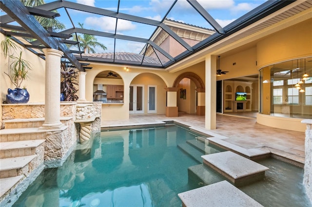 view of swimming pool with french doors, an outdoor kitchen, ceiling fan, glass enclosure, and a patio