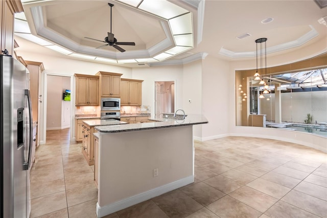 kitchen featuring pendant lighting, an island with sink, appliances with stainless steel finishes, a tray ceiling, and light stone counters