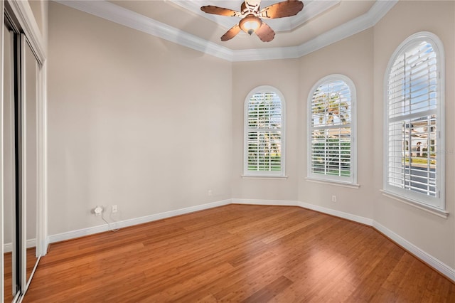 spare room with ceiling fan, light wood-type flooring, ornamental molding, and a tray ceiling