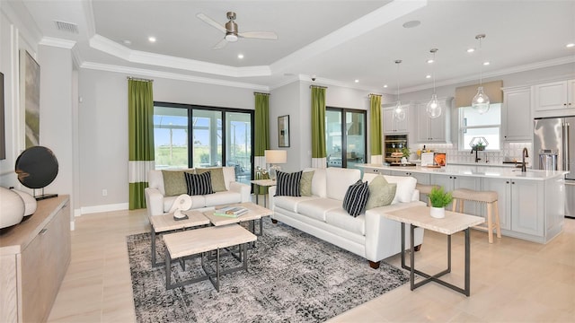 living room with a raised ceiling, ceiling fan, crown molding, and light tile patterned floors