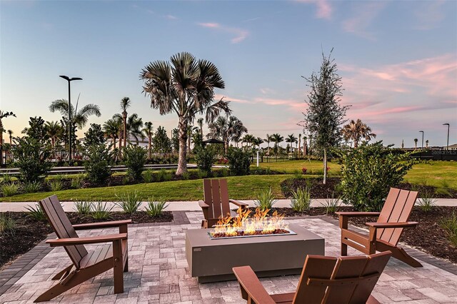 patio terrace at dusk featuring a yard and a fire pit