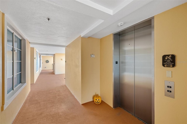 hall with elevator, carpet, and a textured ceiling