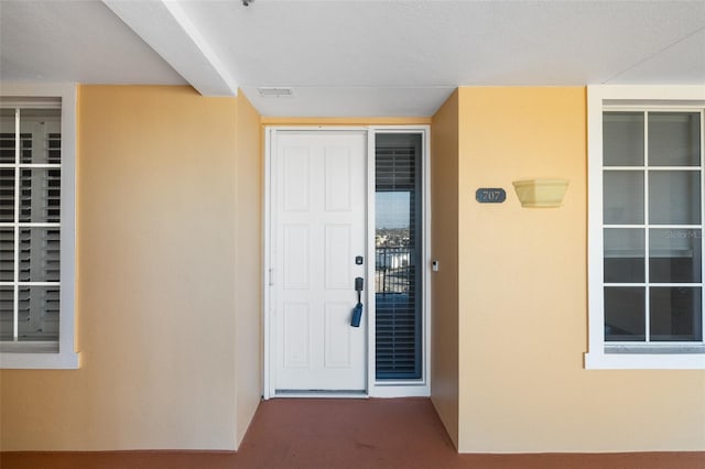 property entrance featuring visible vents and stucco siding