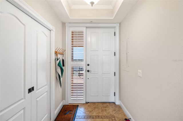 doorway to outside featuring ornamental molding, light tile patterned flooring, and a tray ceiling