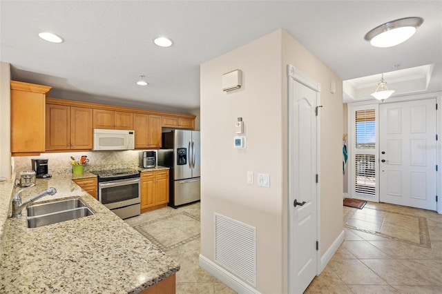 kitchen with light stone countertops, a sink, decorative backsplash, stainless steel appliances, and visible vents