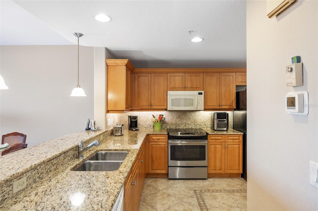 kitchen featuring a sink, white microwave, light stone counters, hanging light fixtures, and stainless steel electric stove