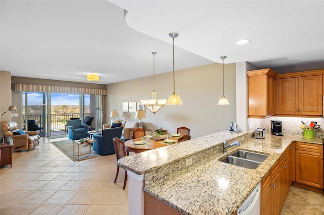 kitchen with light stone counters, decorative light fixtures, dishwasher, a sink, and open floor plan