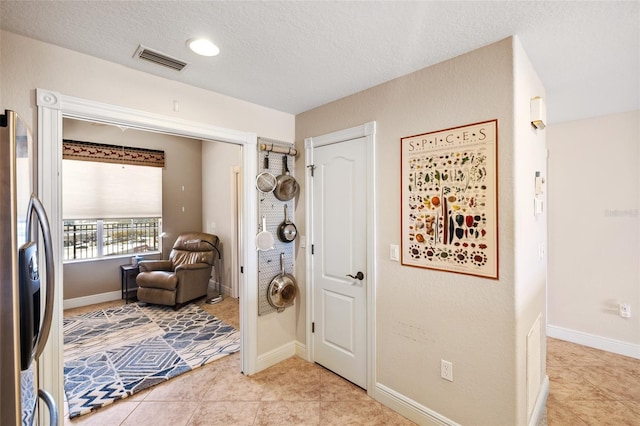 entryway with baseboards, visible vents, a textured ceiling, and light tile patterned flooring