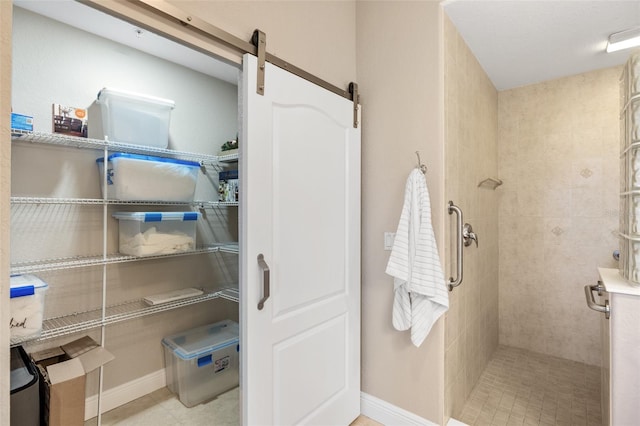 bathroom with a tile shower and baseboards