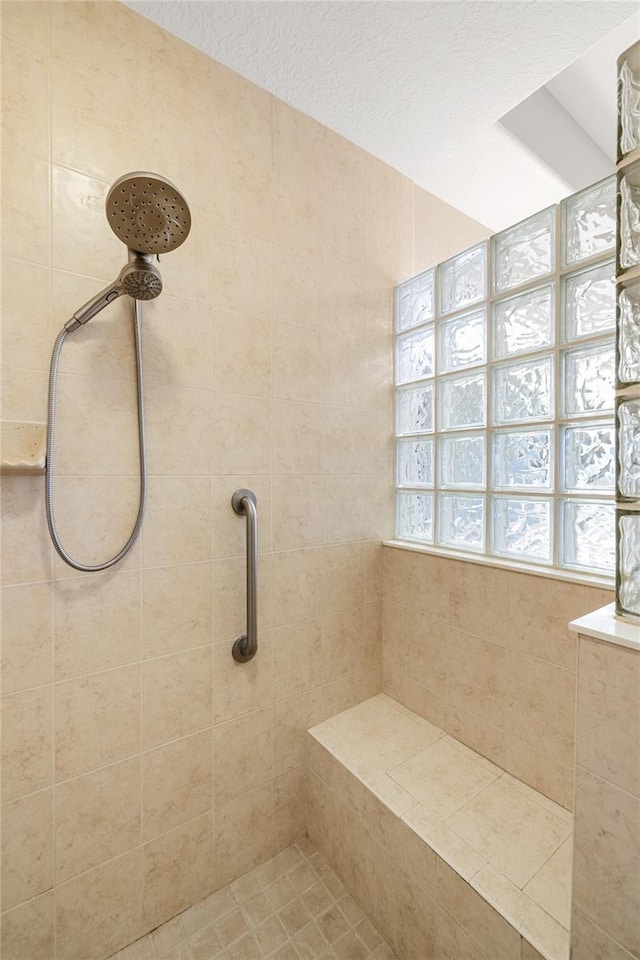 bathroom featuring a textured ceiling and tiled shower