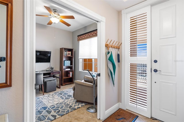 doorway with a ceiling fan, tile patterned floors, and baseboards