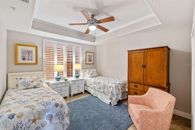 bedroom featuring ornamental molding, ceiling fan, light colored carpet, and a tray ceiling
