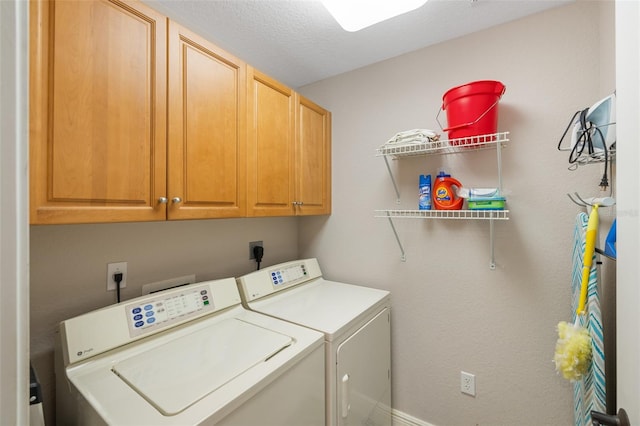 laundry area featuring cabinets, a textured ceiling, and washing machine and clothes dryer