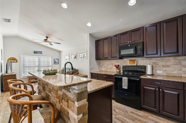 kitchen featuring dark brown cabinets, black appliances, lofted ceiling, and an island with sink