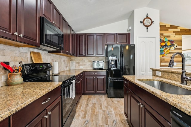 kitchen with lofted ceiling, black appliances, sink, and light wood-type flooring