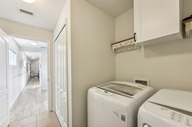 laundry area featuring light tile patterned floors, cabinets, and washing machine and clothes dryer