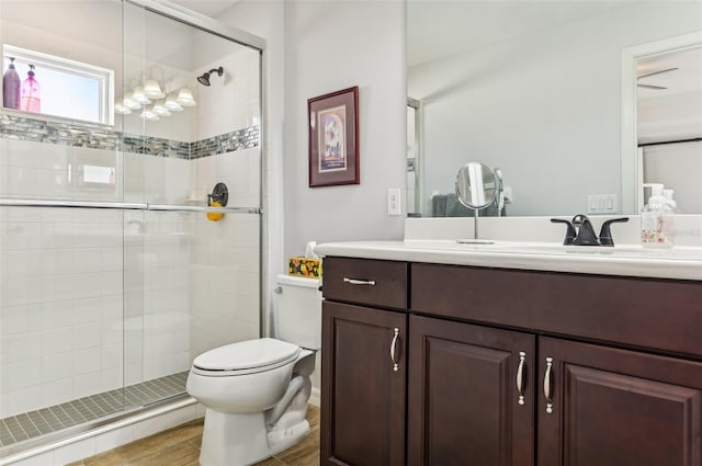 bathroom featuring vanity, hardwood / wood-style flooring, toilet, and a shower with door