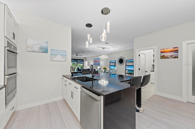 kitchen featuring white cabinetry, sink, stainless steel appliances, and light hardwood / wood-style floors