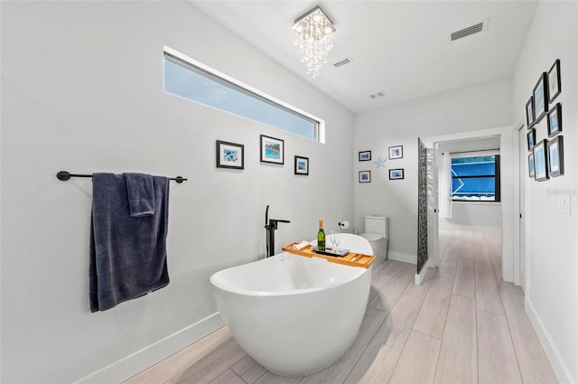 bathroom featuring a bath, a chandelier, wood-type flooring, and toilet