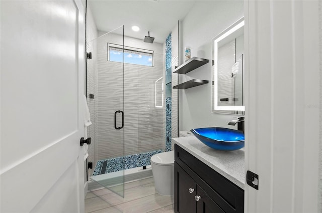 bathroom featuring vanity, a shower with shower door, and toilet