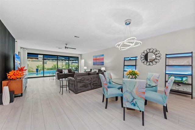 dining space featuring ceiling fan with notable chandelier and light hardwood / wood-style floors