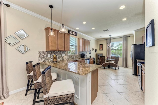 kitchen with kitchen peninsula, decorative light fixtures, stainless steel appliances, a breakfast bar, and dark stone counters