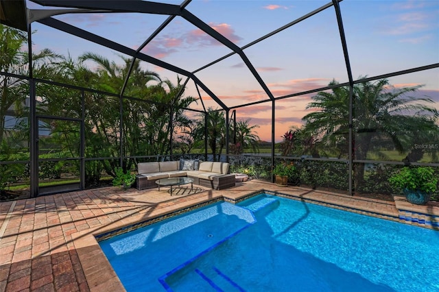 pool at dusk with a lanai, an outdoor hangout area, and a patio area