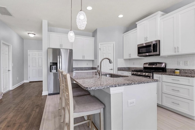 kitchen featuring white cabinets, stainless steel appliances, sink, and a kitchen island with sink