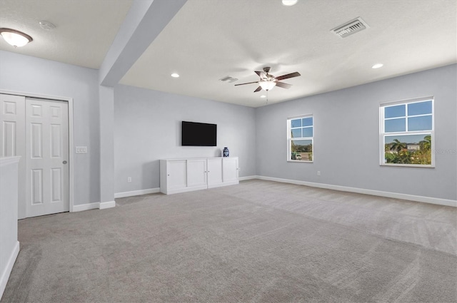 unfurnished living room featuring a textured ceiling, light colored carpet, and ceiling fan