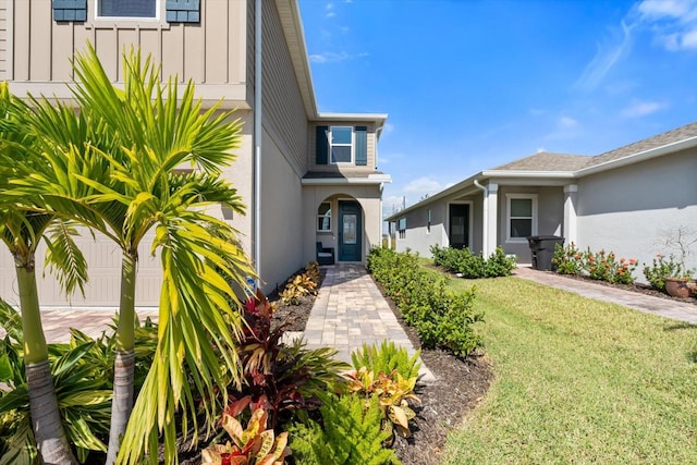 entrance to property featuring a yard and a garage