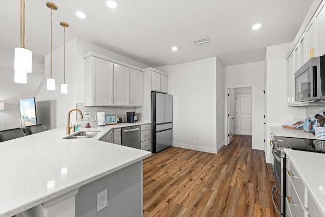 kitchen with sink, white cabinetry, stainless steel appliances, decorative light fixtures, and dark wood-type flooring