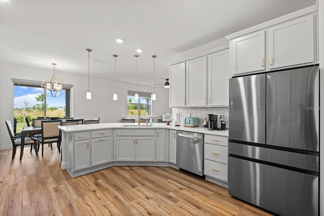 kitchen featuring appliances with stainless steel finishes, white cabinetry, a wealth of natural light, and pendant lighting