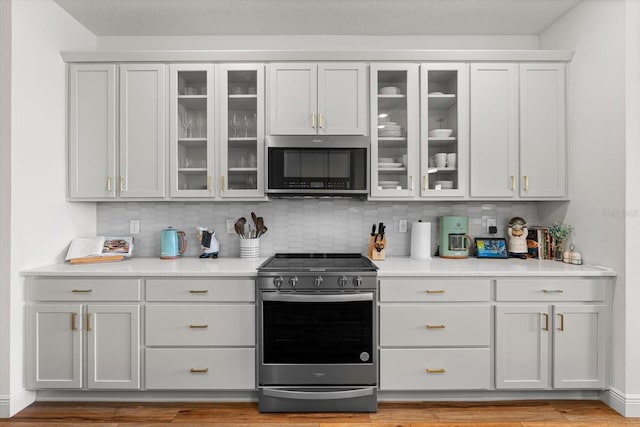 kitchen with appliances with stainless steel finishes, light hardwood / wood-style flooring, backsplash, and white cabinets