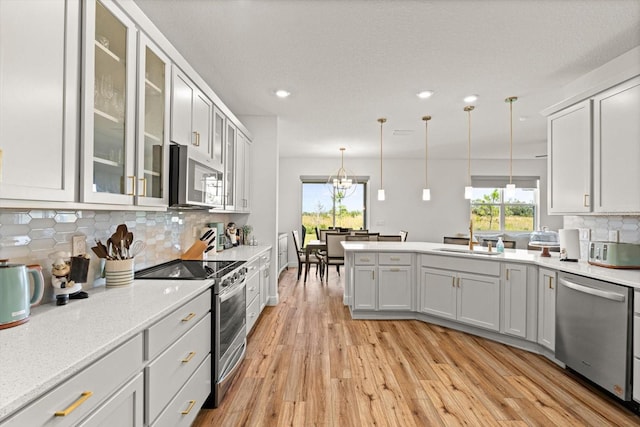 kitchen featuring light hardwood / wood-style floors, white cabinets, stainless steel appliances, and pendant lighting