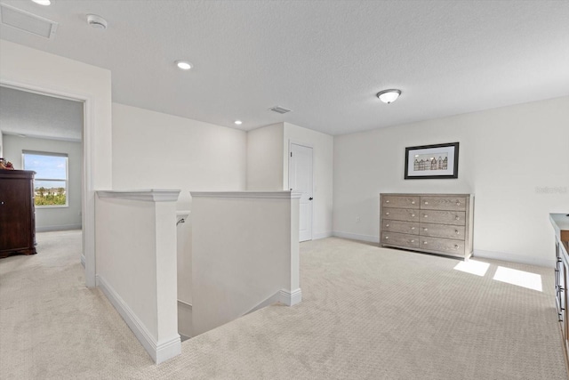 hallway featuring a textured ceiling and light colored carpet