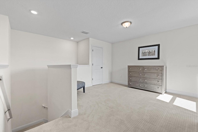 interior space with a textured ceiling and light colored carpet